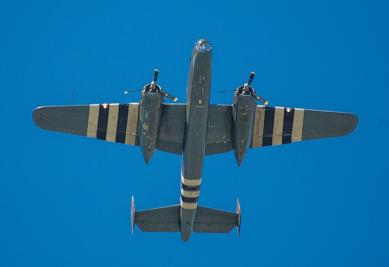 B-25 Mitchell warbird bomber painted in D-Day invasion stripes, parked on the ramp