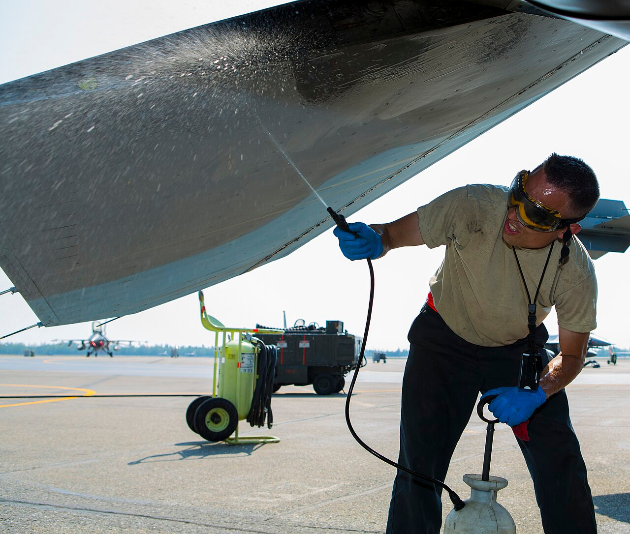 Ground crew performing flight line maintenance on a military aircraft on the apron
