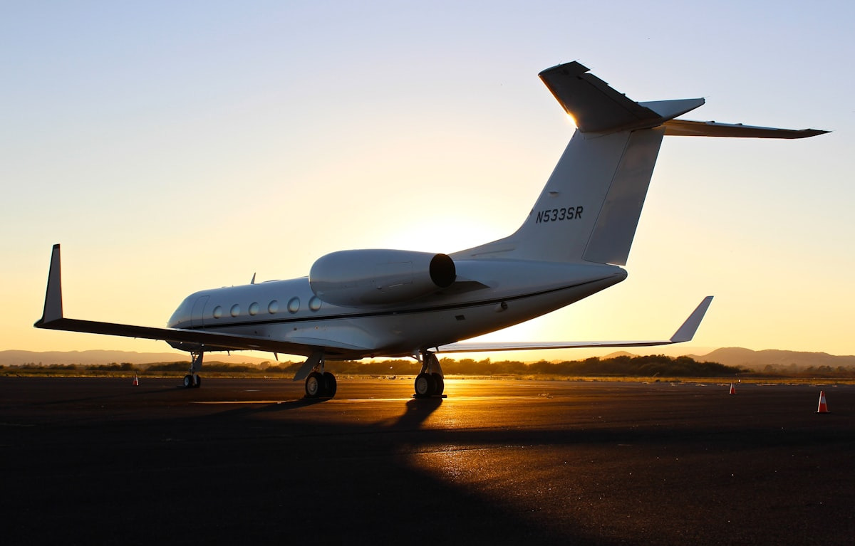 Jet aircraft on the ramp at golden hour, low sun flaring behind the tail